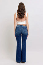 Woman wearing blue jeans and a white top on a plain background