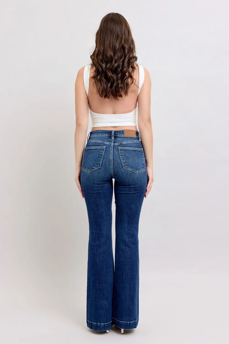 Woman wearing blue jeans and a white top on a plain background