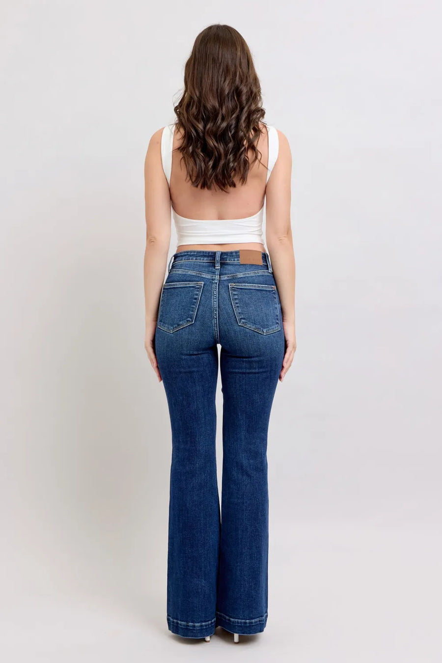 Woman wearing blue jeans and a white top on a plain background