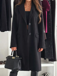 Person wearing a black coat with a handbag in a clothing store setting