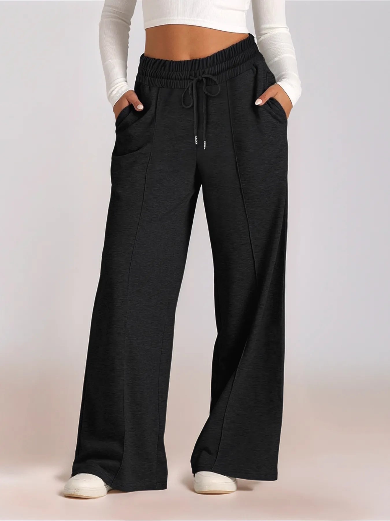 Black wide-leg pants worn by a person on a light pink background