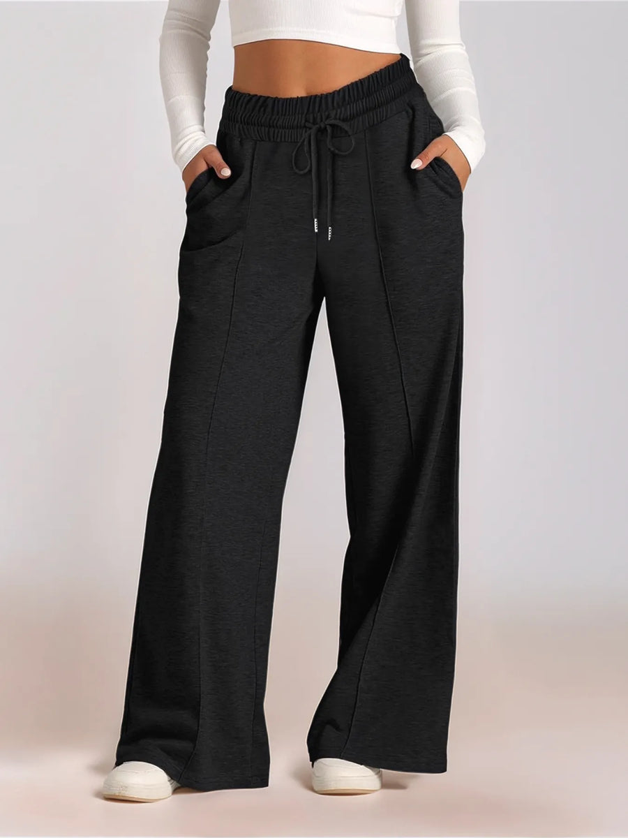 Black wide-leg pants worn by a person on a light pink background