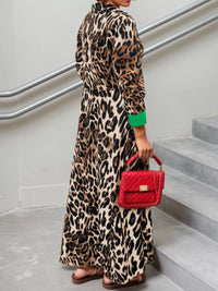 Person wearing a leopard print dress holding a red handbag on a staircase.