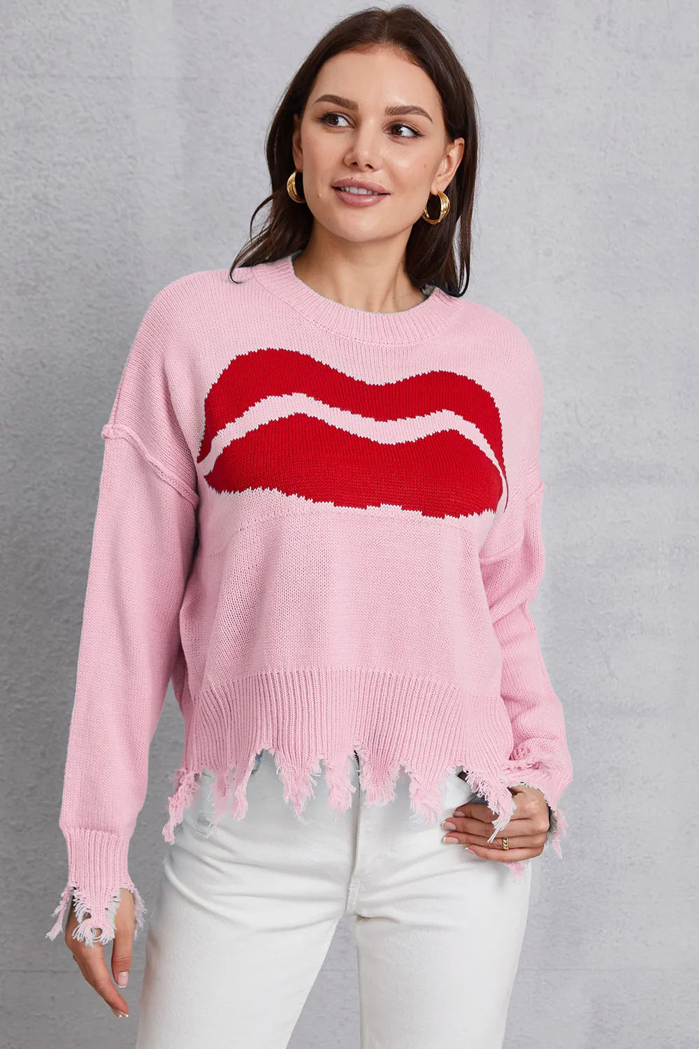 Woman wearing a pink sweater with red lips design against a gray background