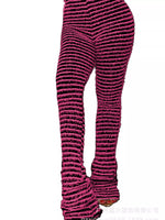 A close-up side view of a person wearing textured, ribbed knit leggings in a dark pink and black striped pattern, cropped from the waist down against a plain white background.