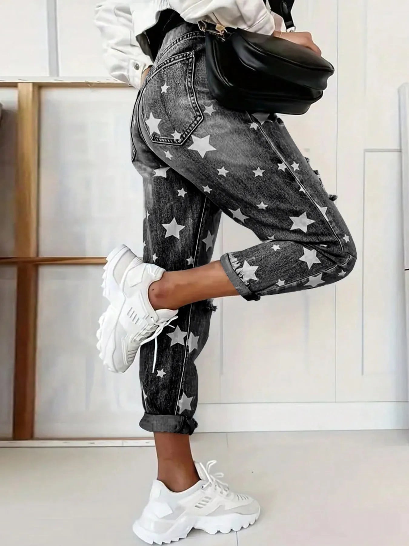 Person wearing star-patterned jeans and white sneakers in a minimal indoor setting