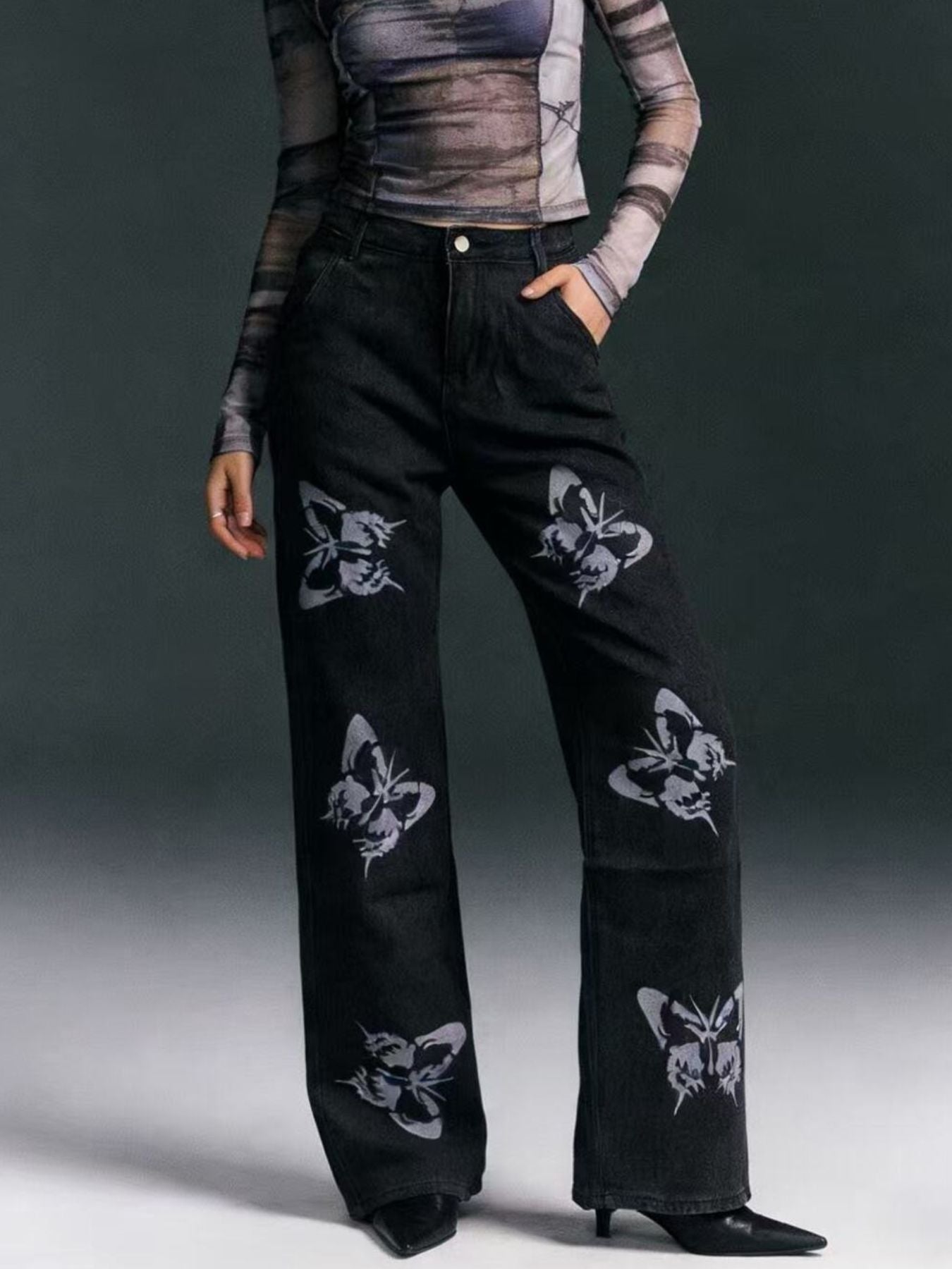 Black pants with butterfly patterns worn by a person on a gray background