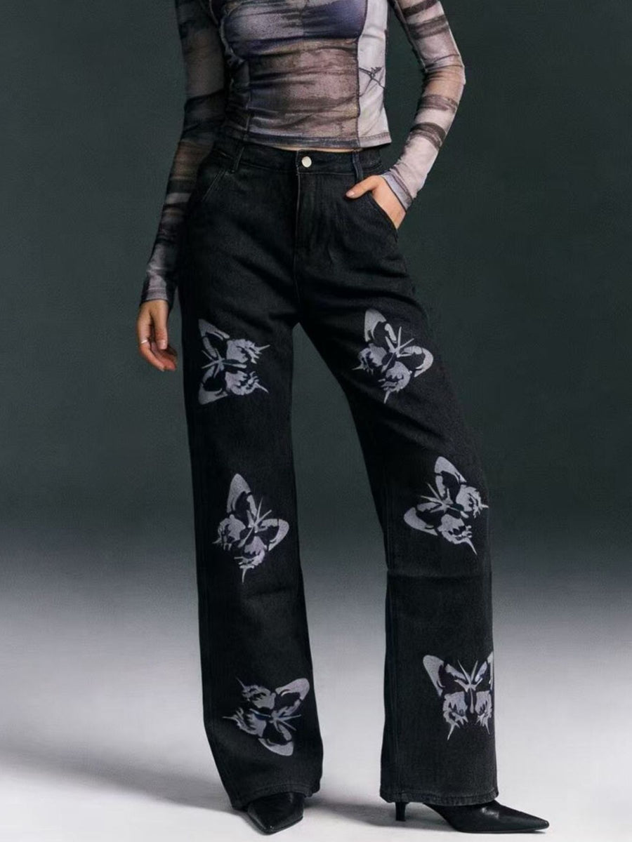 Black pants with butterfly patterns worn by a person on a gray background