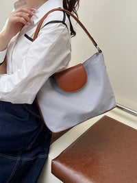 Person holding a white handbag with brown leather accents