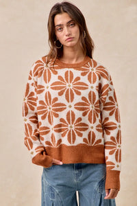 Woman wearing a brown and white patterned sweater with blue jeans on a beige background