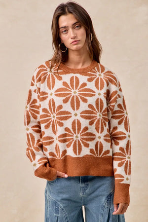 Woman wearing a brown and white patterned sweater with blue jeans on a beige background
