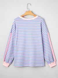 Blue and pink striped long-sleeve shirt on a hanger against a gray background