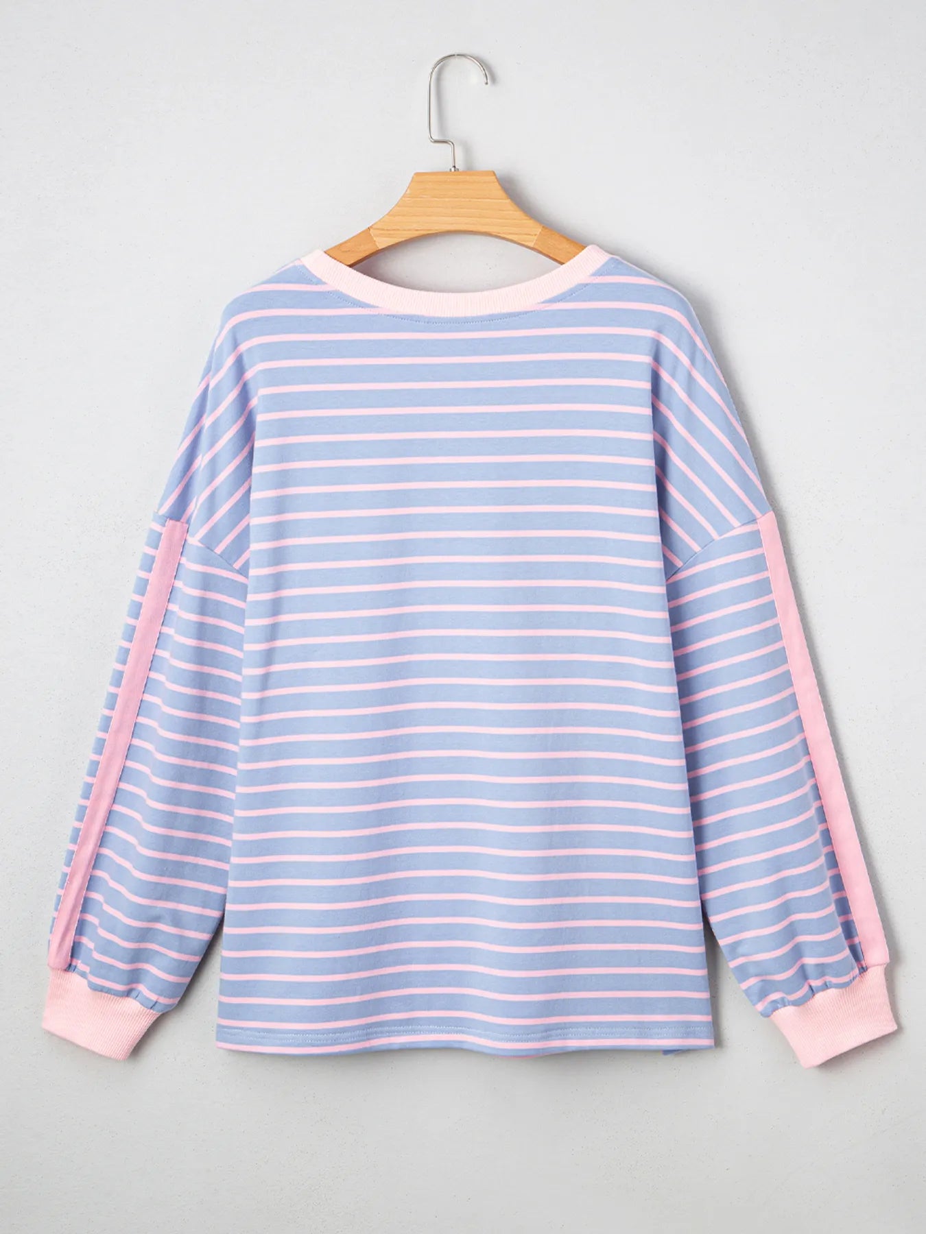 Blue and pink striped long-sleeve shirt on a hanger against a gray background