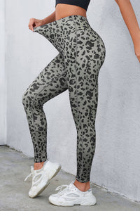 Person wearing gray leopard print leggings with white sneakers against a light gray wall.