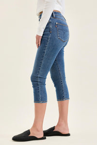 Person wearing blue jeans and black slides on a plain background
