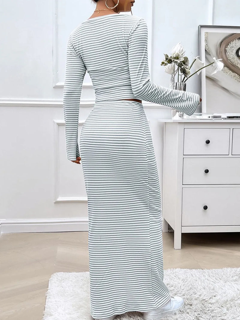 Woman wearing a long, striped dress in a room with white walls and furniture.