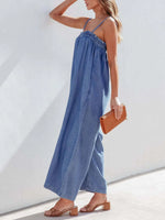 Woman wearing a blue denim jumpsuit with a white background
