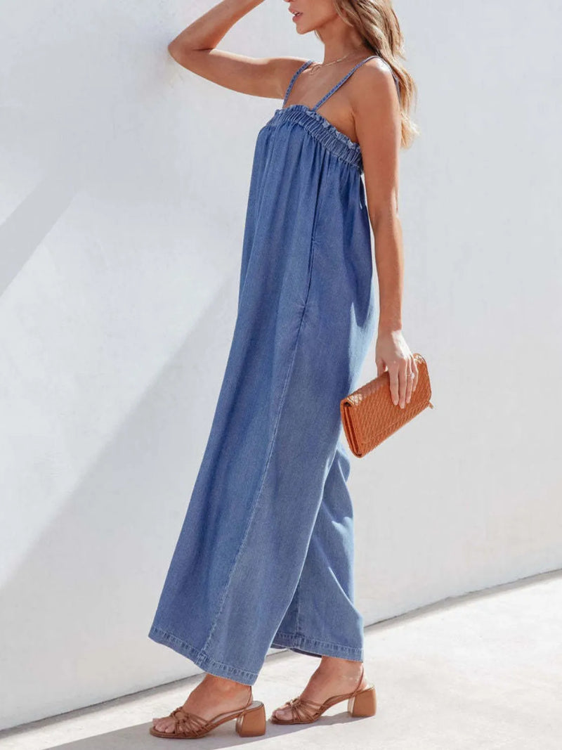 Woman wearing a blue denim jumpsuit with a white background
