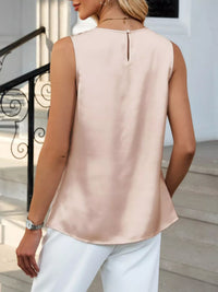 Woman wearing a light pink sleeveless top and white pants outdoors.