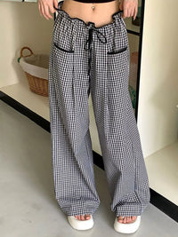 Person wearing black and white checkered pants in a minimal indoor setting.