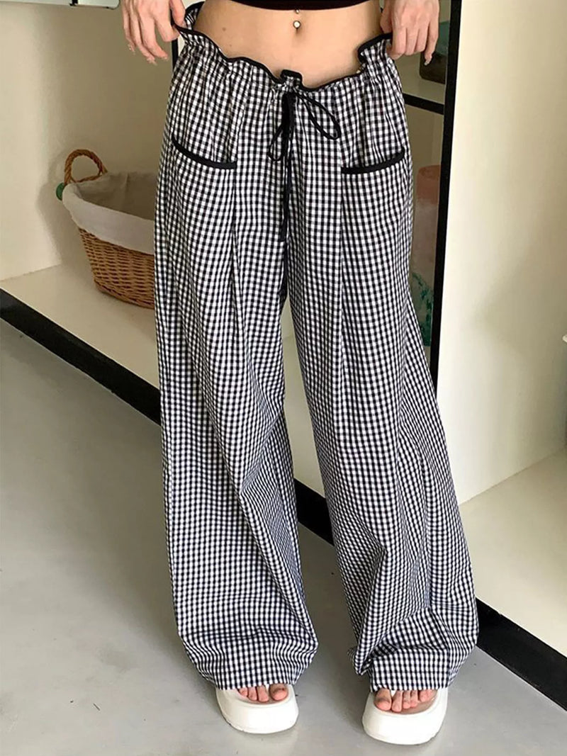 Person wearing black and white checkered pants in a minimal indoor setting.