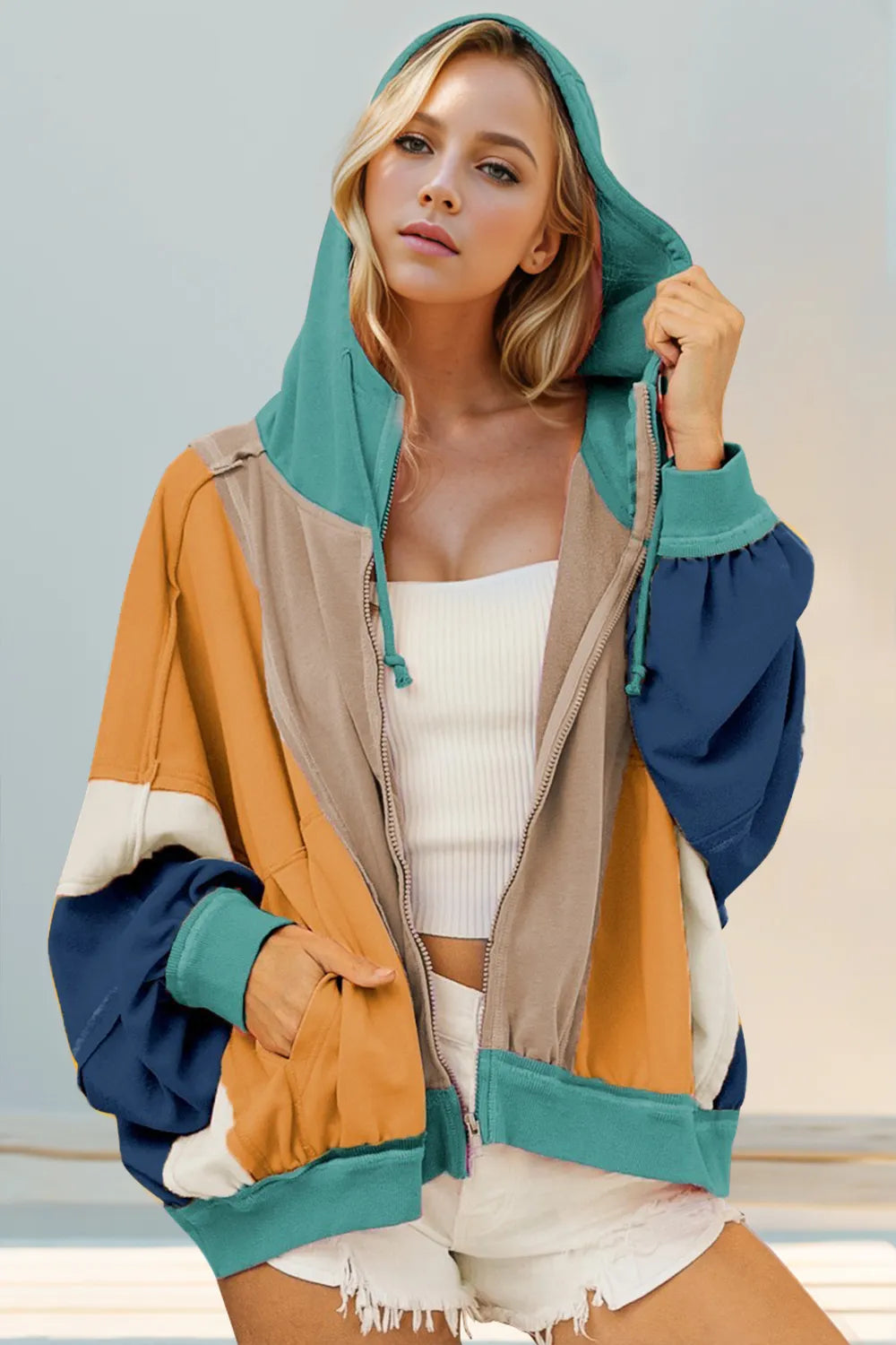 Woman wearing a colorful hooded jacket with a neutral background