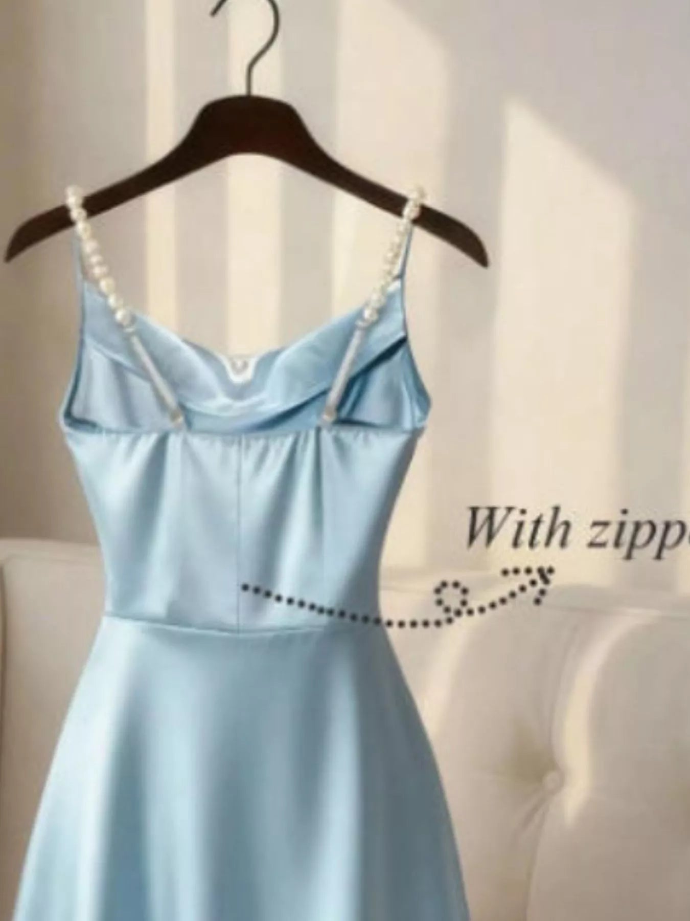 Light blue dress with pearl straps on a hanger against a neutral background