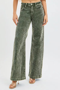 Person wearing green acid-wash jeans on a white background