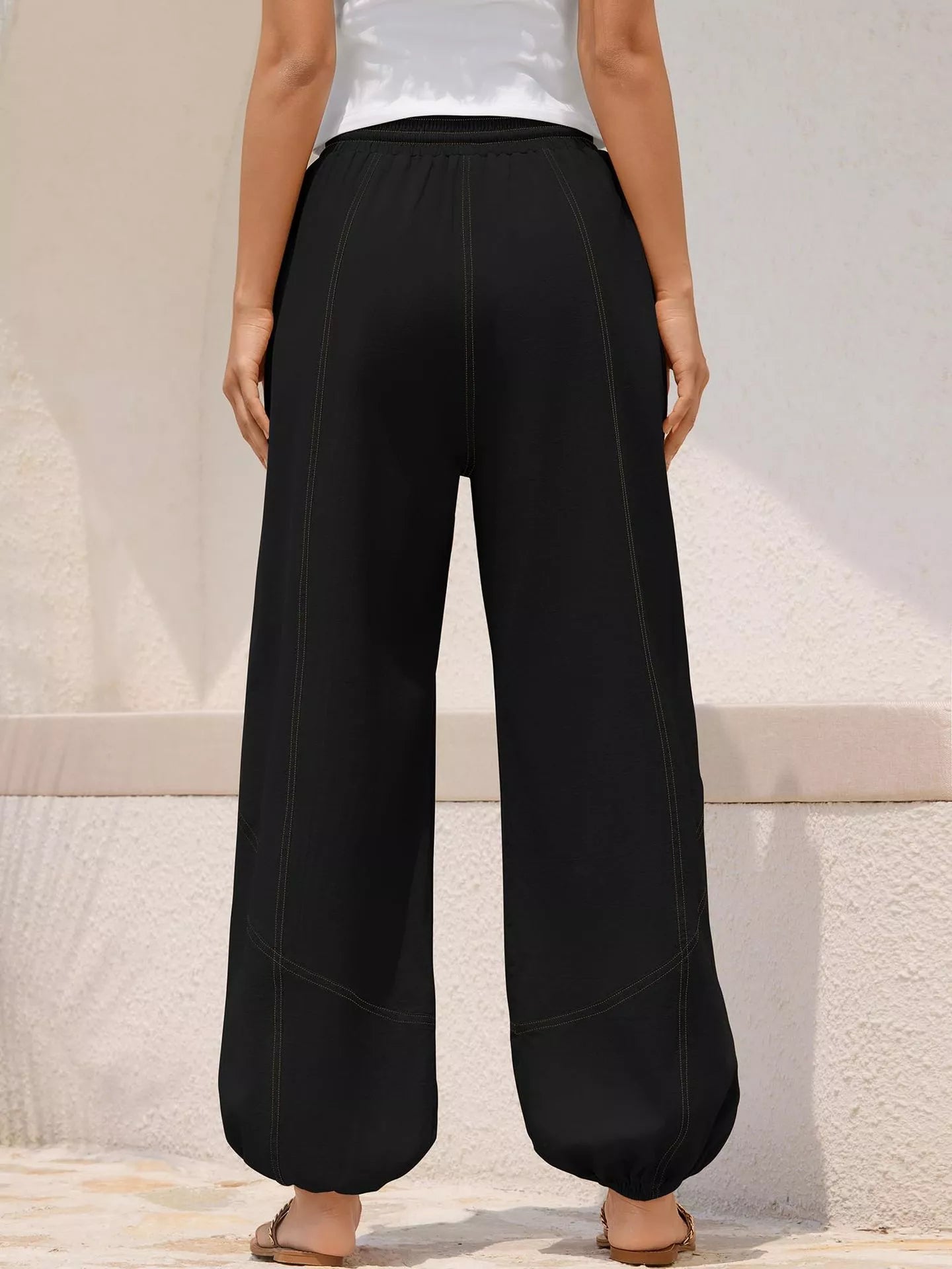 Person wearing black wide-leg pants against a neutral background