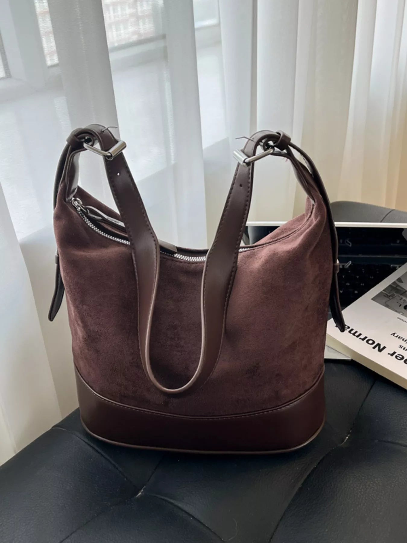 Brown handbag on a black surface with a blurred background