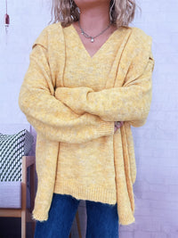 Person wearing a yellow sweater with a white brick wall background
