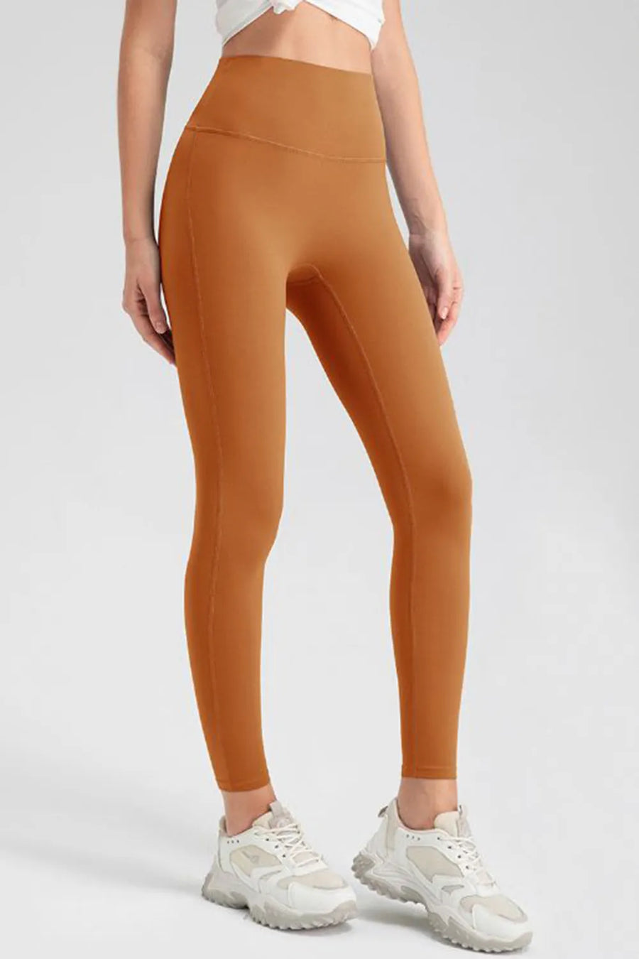 Person wearing orange leggings with a white background