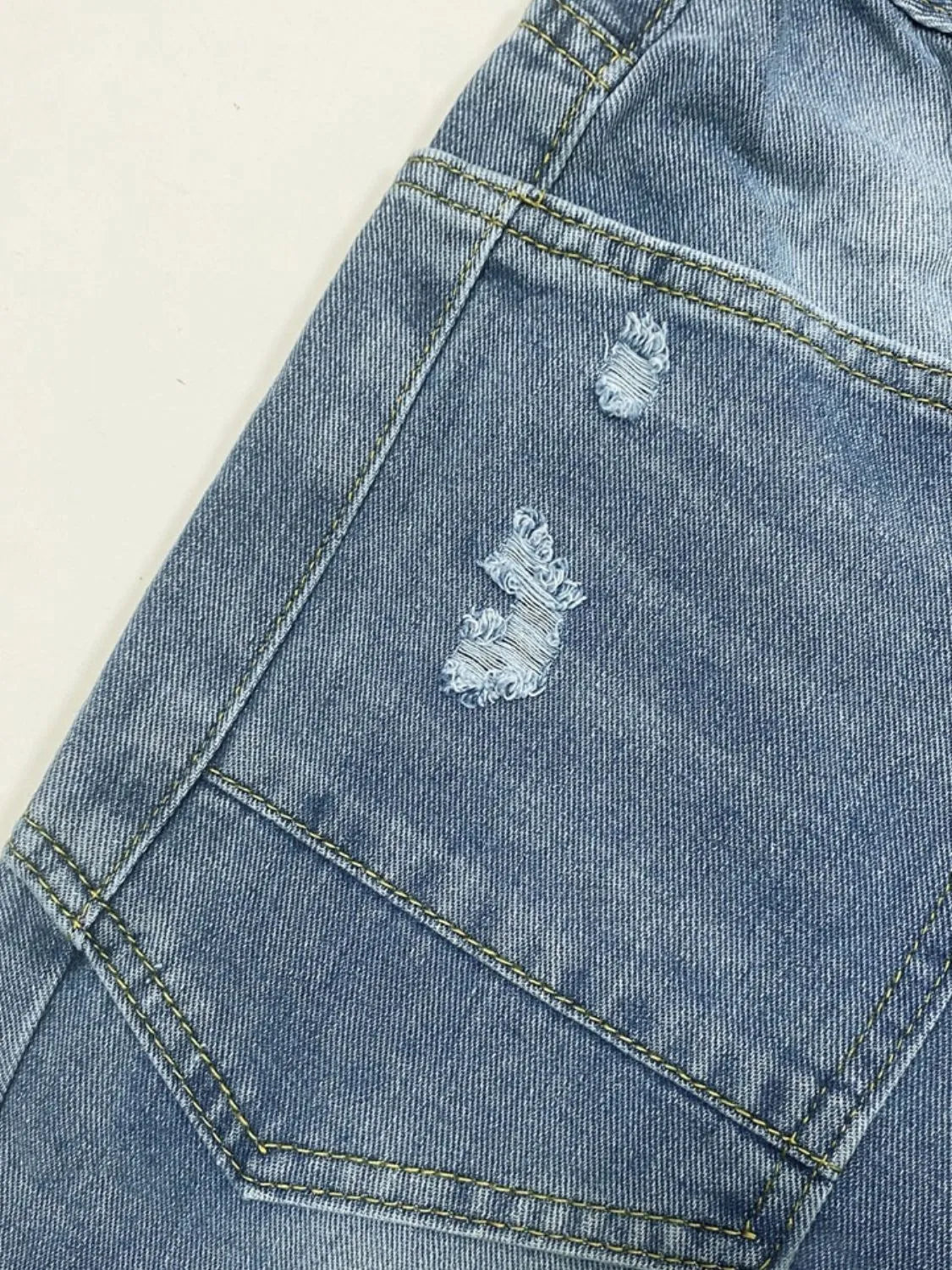 Close-up of a blue denim jacket with distressed details on a light background