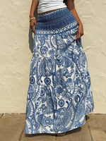 Person wearing a blue and white patterned skirt against a beige wall.