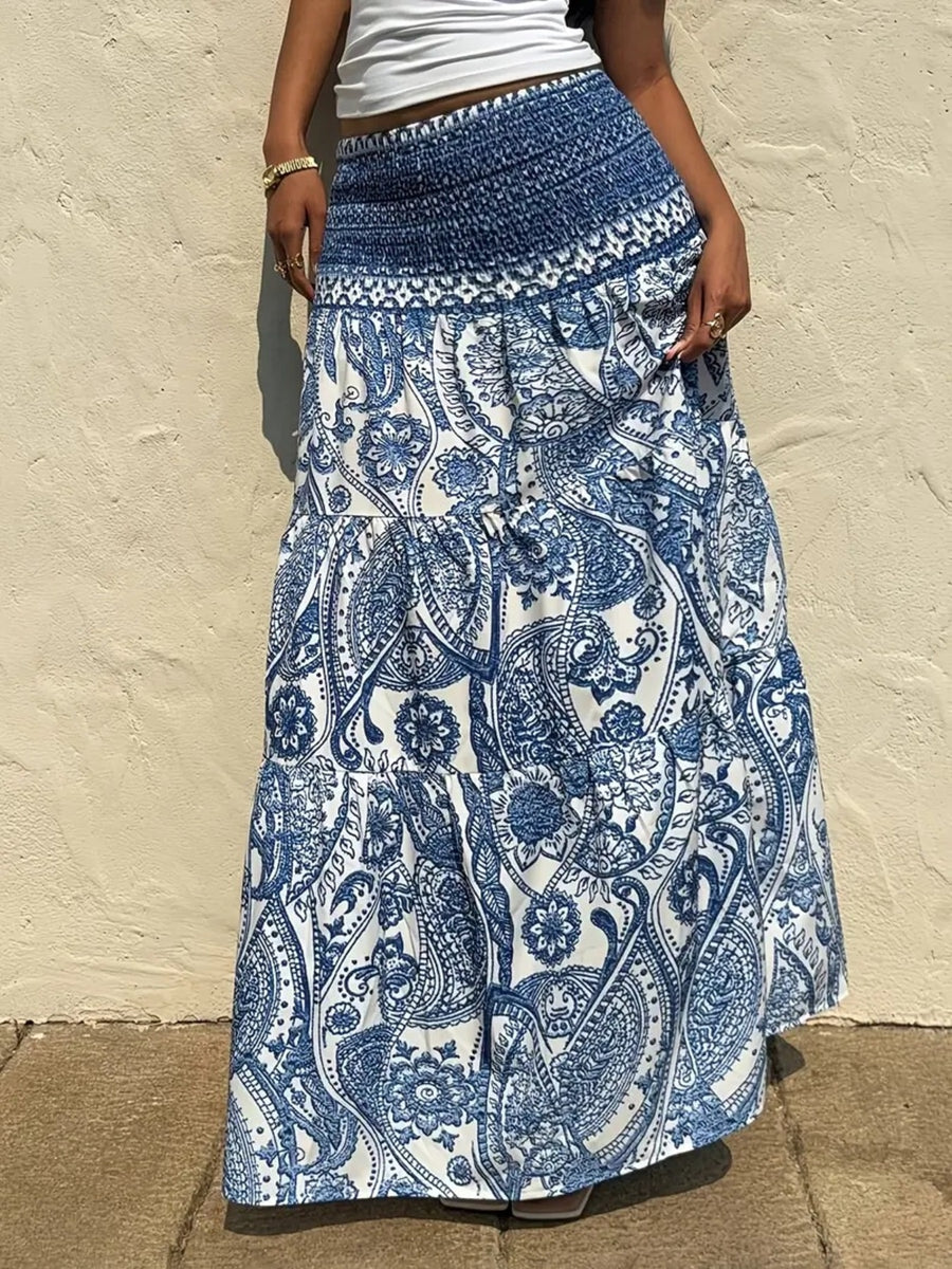 Person wearing a blue and white patterned skirt against a beige wall.