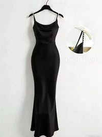 Black slip dress on a hanger against a white background
