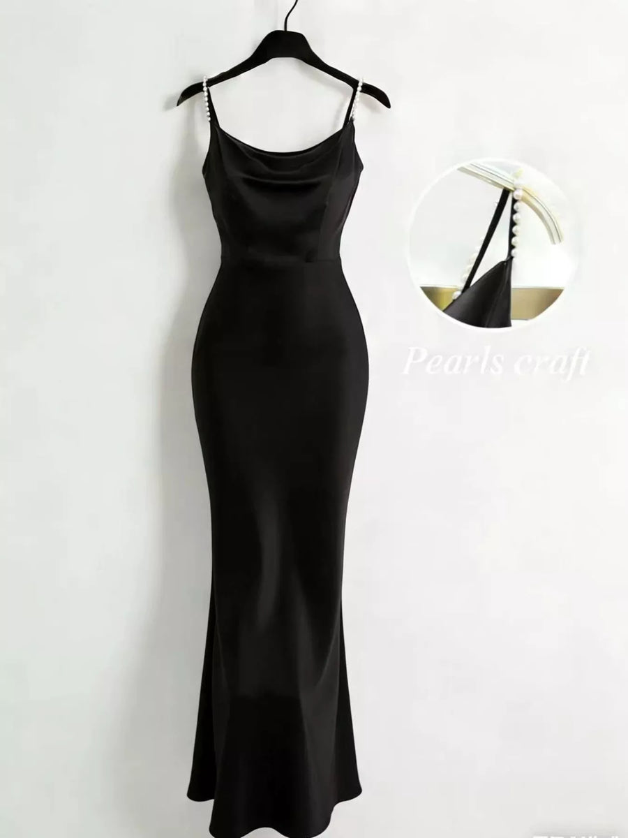 Black slip dress on a hanger against a white background