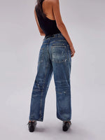 Person wearing blue jeans and a black top on a plain background