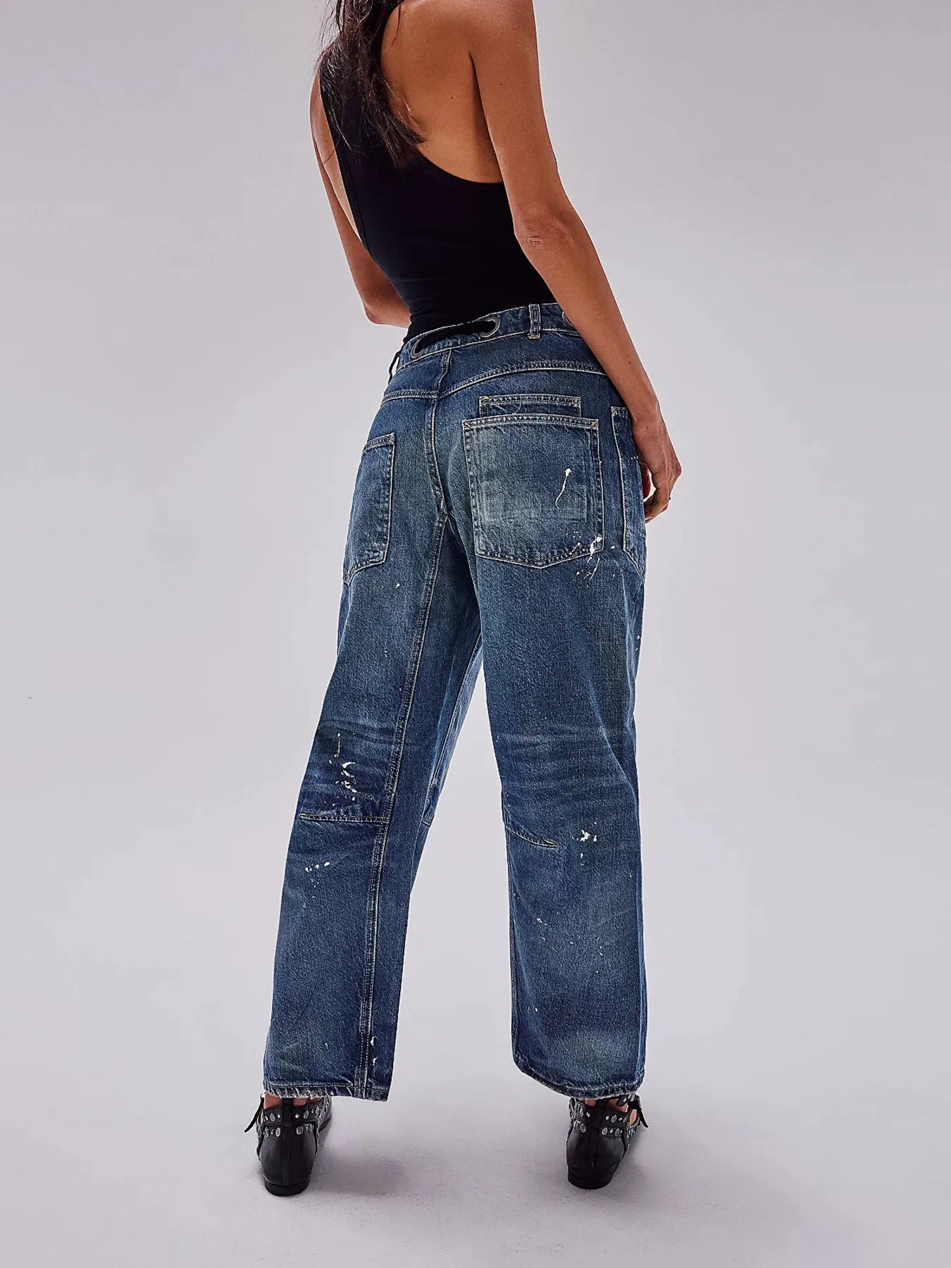 Person wearing blue jeans and a black top on a plain background