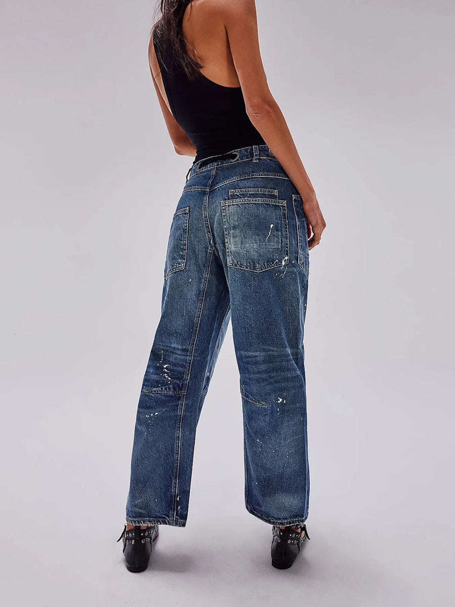 Person wearing blue jeans and a black top on a plain background