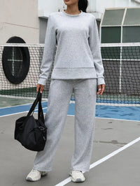 Person wearing a gray tracksuit on a tennis court
