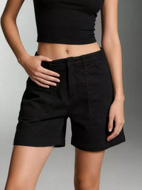 Person wearing black shorts and a black crop top on a gray background