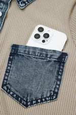 White phone with black camera details in a blue denim pocket of a beige jacket.