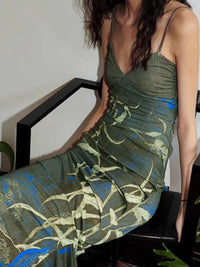 Woman wearing a green floral dress sitting on a black chair.