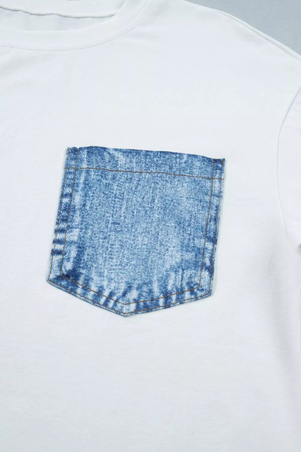 White t-shirt with a blue denim pocket design on a white background