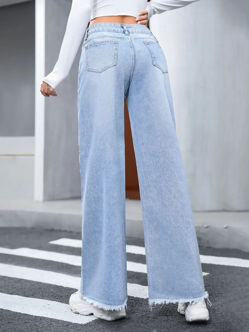 Light blue jeans worn by a person on a street with white lines.