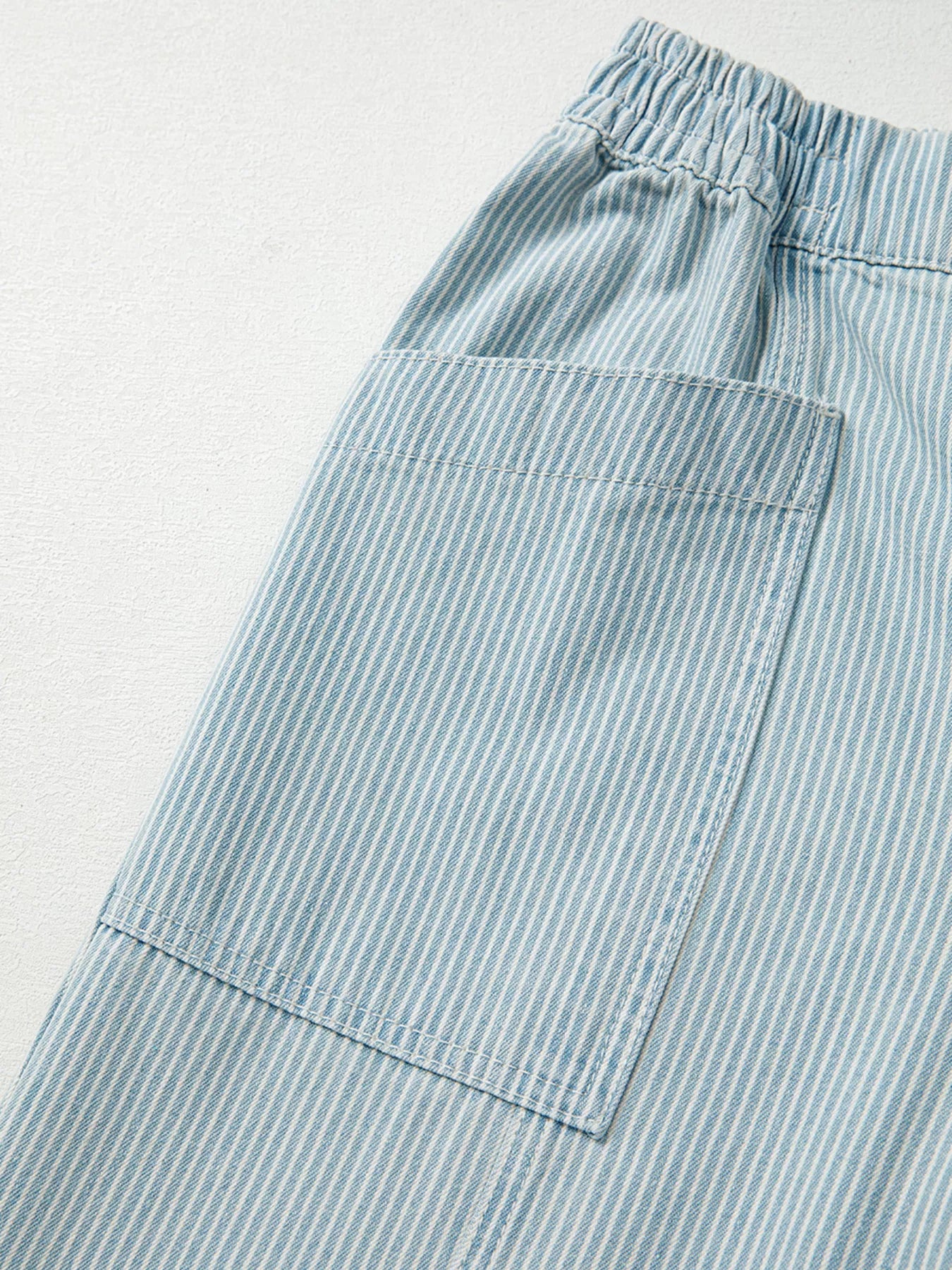 Light blue striped pants with a pocket on a light gray background