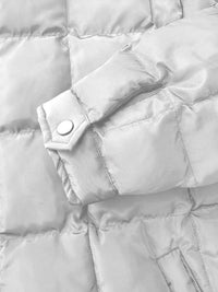 Close-up of a light gray puffer jacket with a button detail.