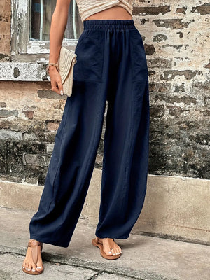 Person wearing navy wide-leg pants standing against a textured wall.