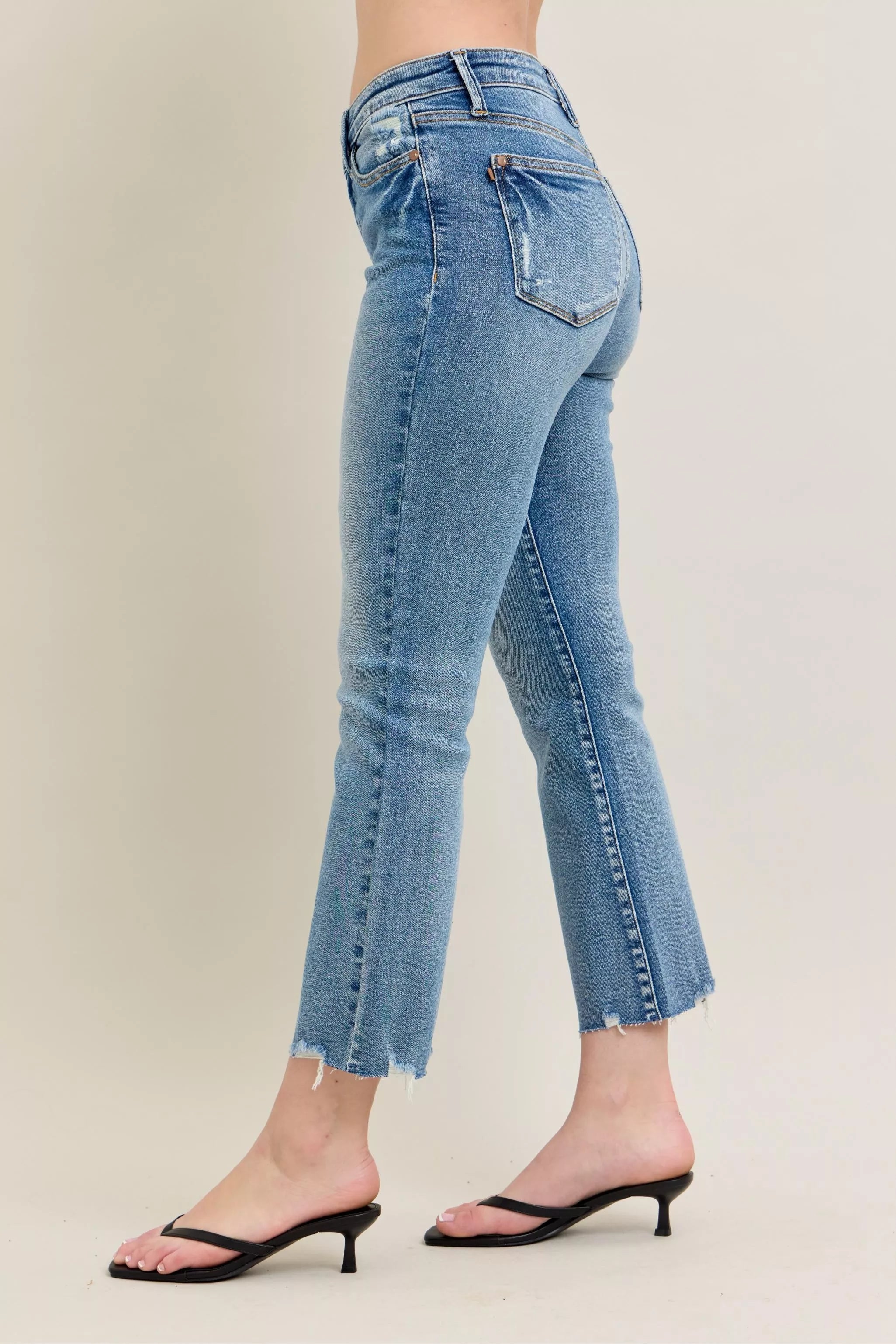 Blue jeans with a cropped hem on a plain background